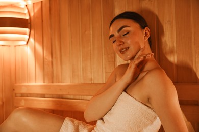 Beautiful woman wrapped in towel at sauna