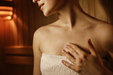 Photo of Young woman relaxing in hot sauna, closeup