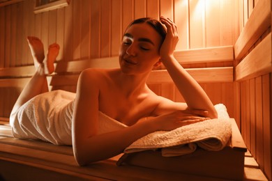 Beautiful woman lying on bench in sauna