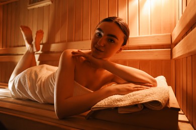 Beautiful woman lying on bench in sauna