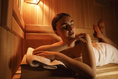 Beautiful woman lying on bench in sauna