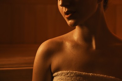 Young woman relaxing in hot sauna, closeup. Space for text