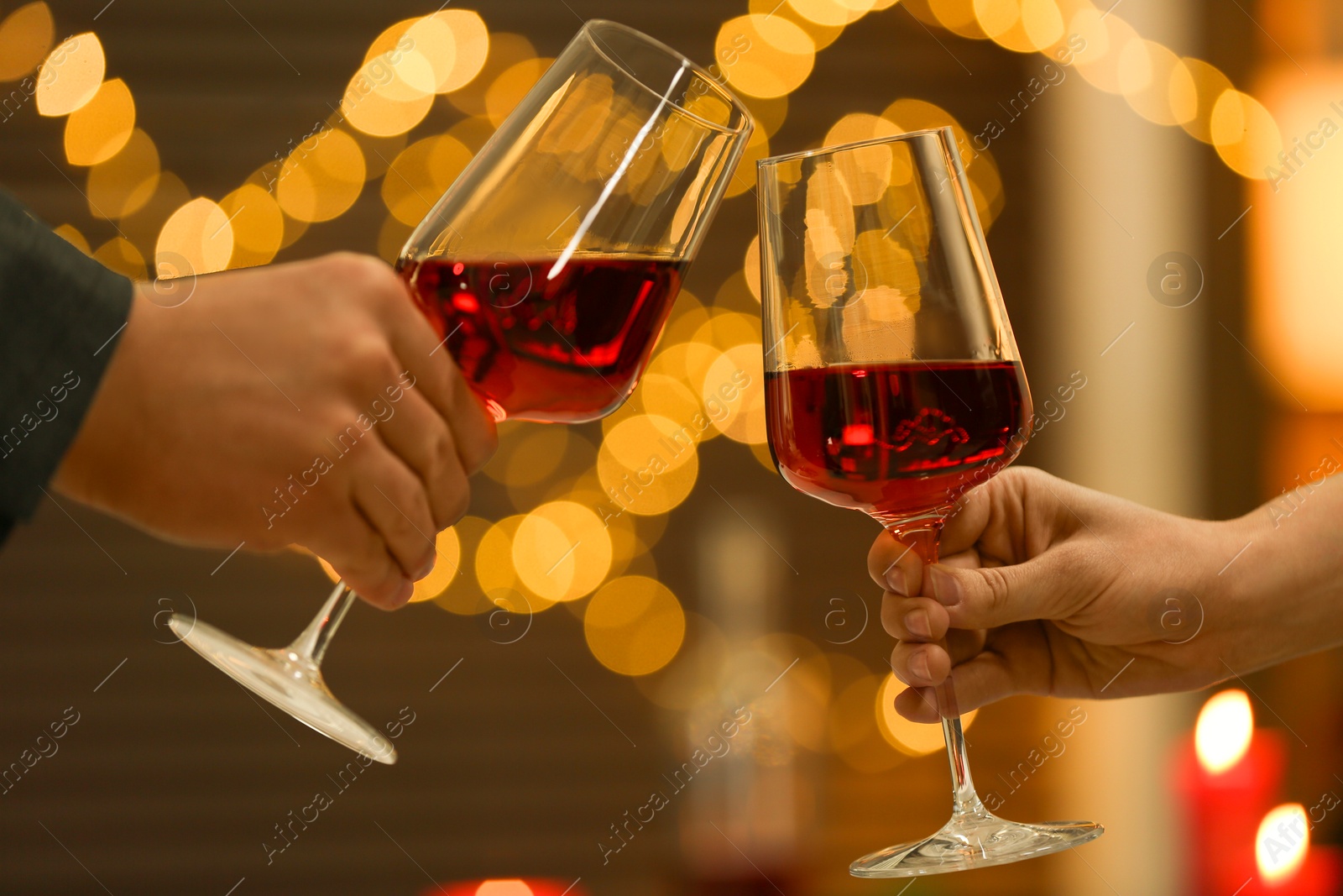 Photo of Couple clinking glasses of wine against blurred lights , closeup. Romantic dinner