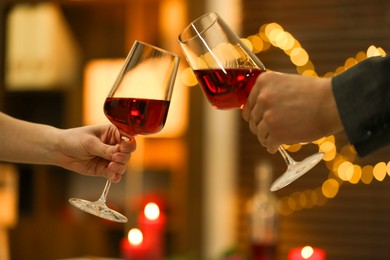 Photo of Couple clinking glasses of wine in restaurant, closeup. Romantic dinner