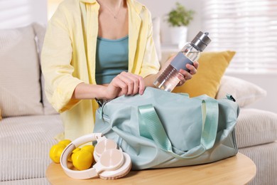 Woman packing her gym bag at home, closeup