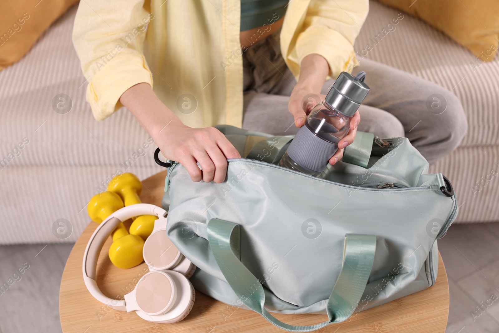 Photo of Woman packing her gym bag at home, closeup