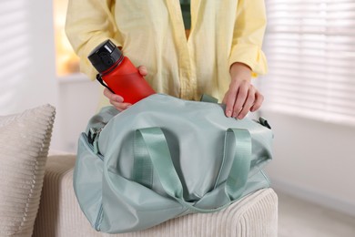 Woman packing her gym bag at home, closeup