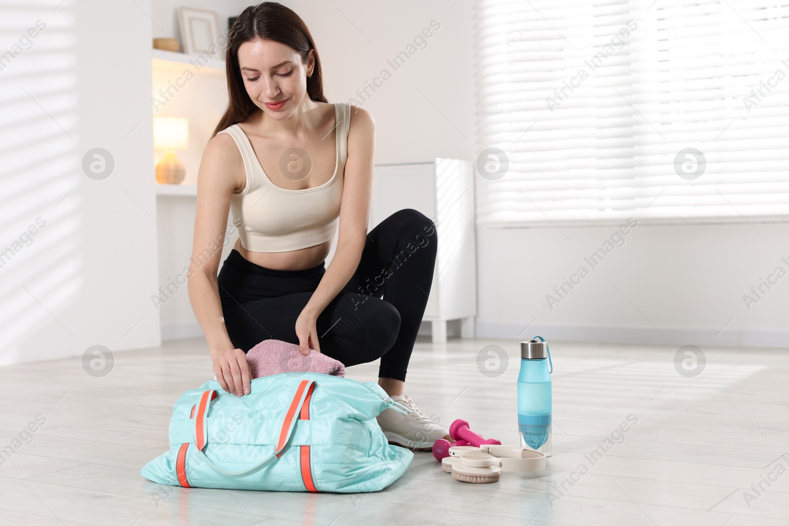 Photo of Happy woman packing her gym bag at home. Space for text