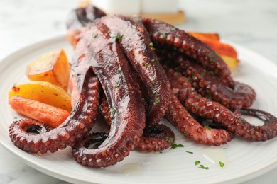 Photo of Roasted octopus with vegetables on table, closeup