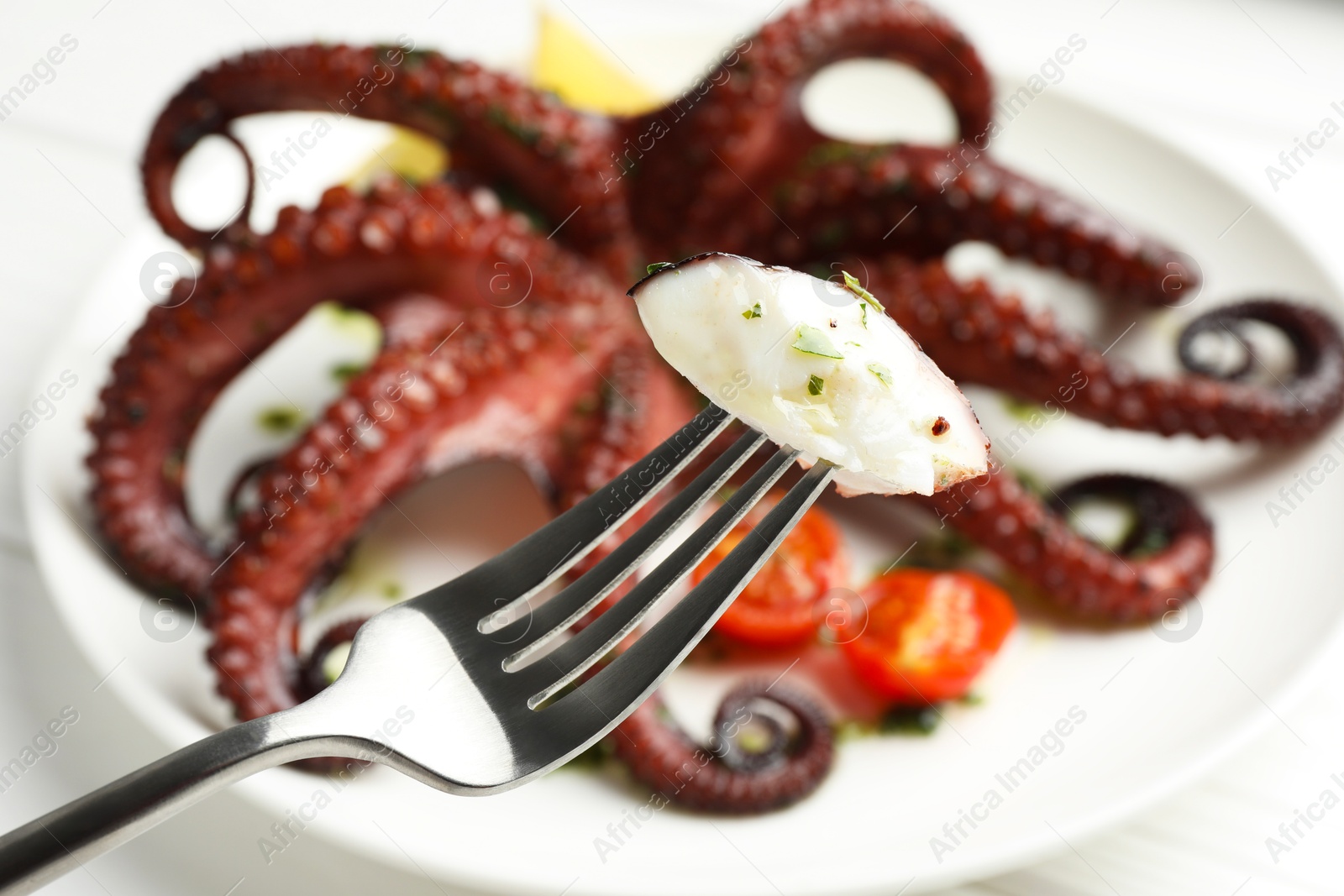 Photo of Eating tasty fried octopus with herb sauce at white table, closeup