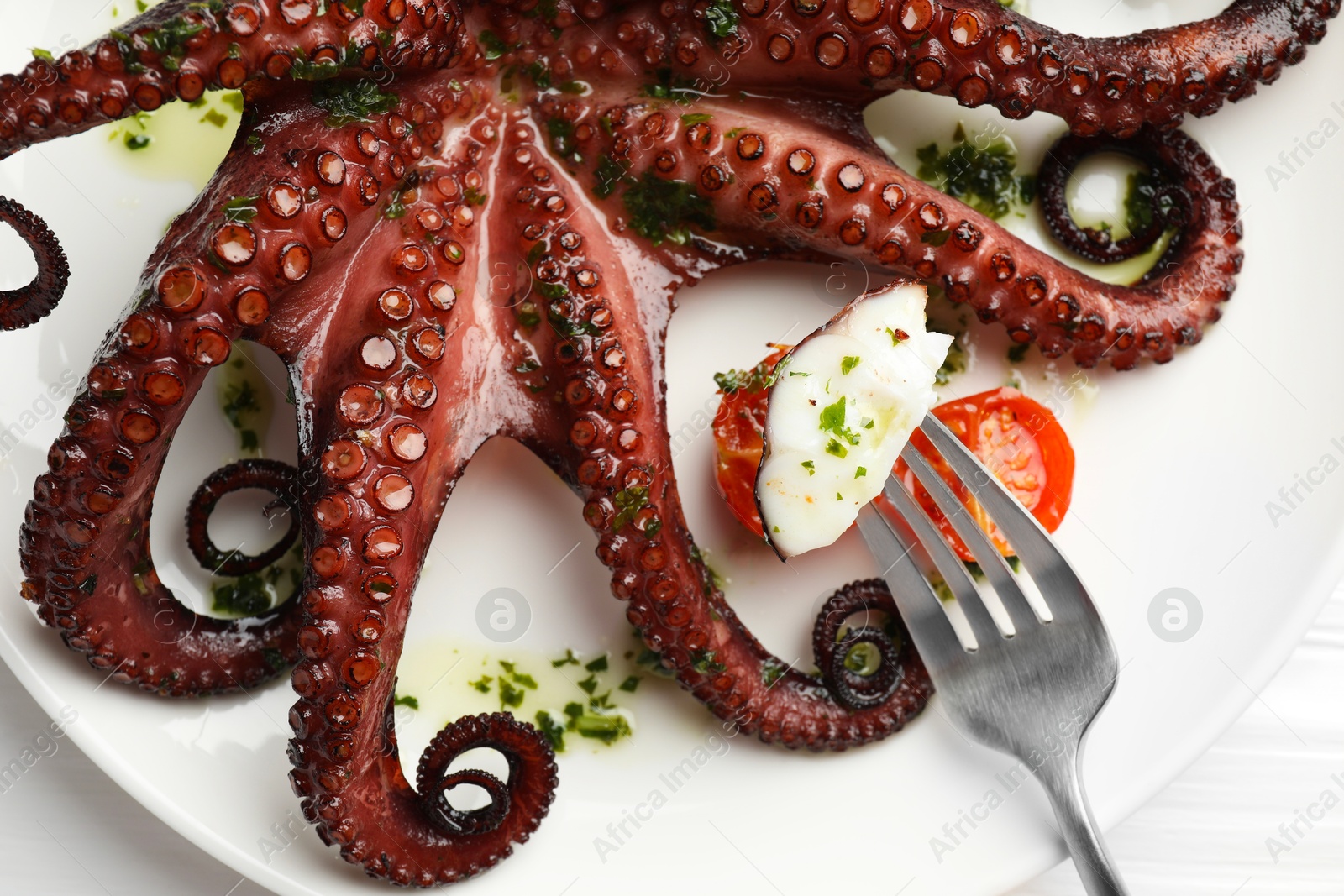 Photo of Eating tasty fried octopus with herb sauce at white table, top view