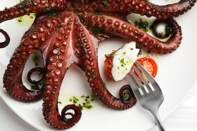 Photo of Eating tasty fried octopus with herb sauce at white table, top view