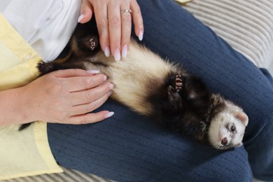 Photo of Woman with cute ferret on sofa, above view
