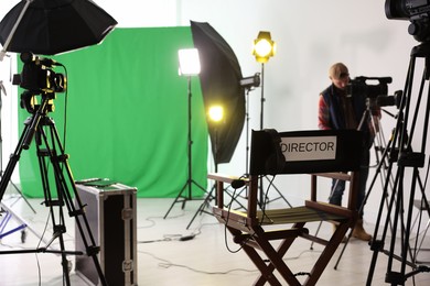 Photo of Man working in modern film studio with professional equipment, focus on chair with word Director