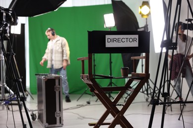 Photo of People working in modern film studio, focus on chair with word Director