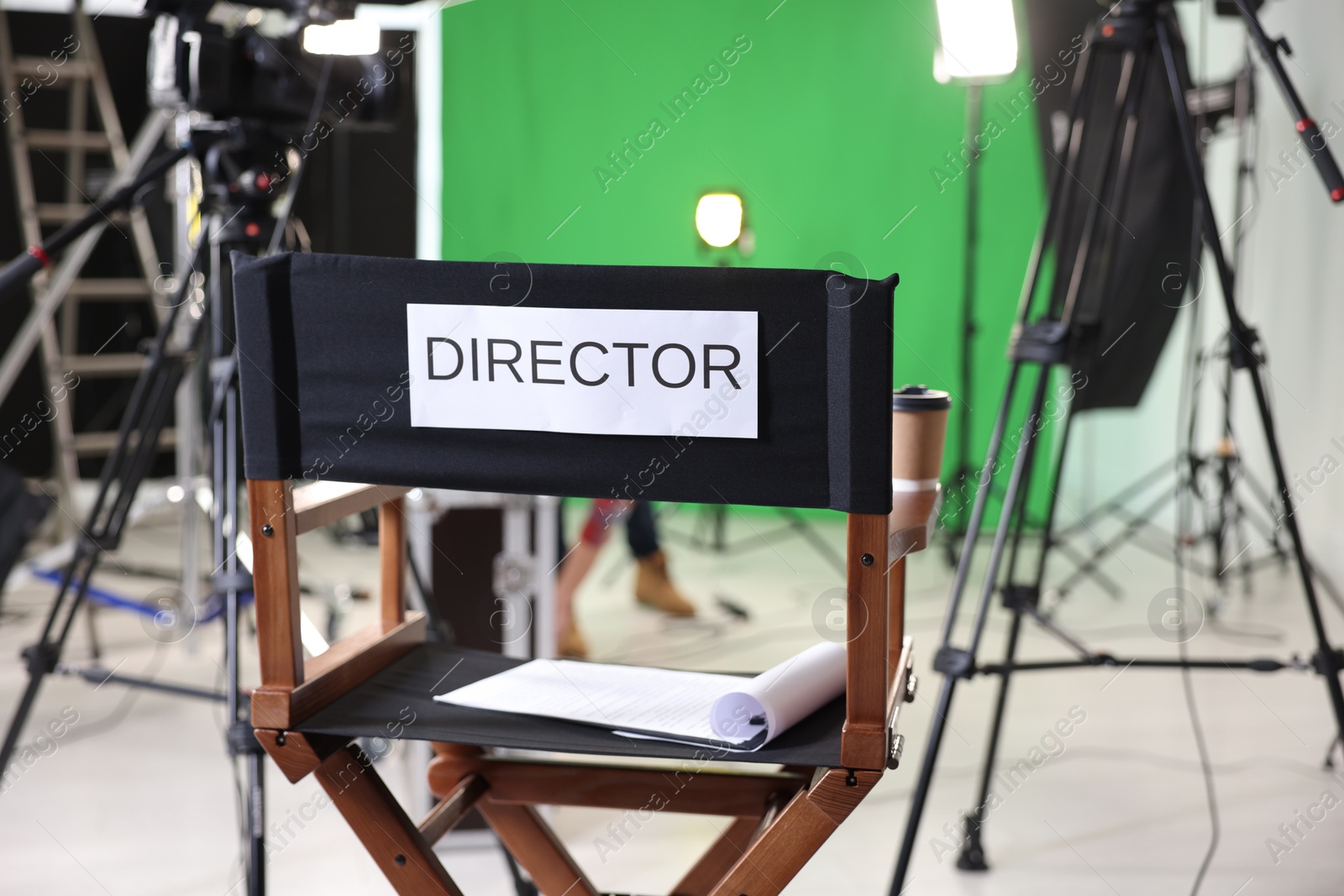 Photo of Chair with word Director, clipboard and professional equipment in modern film studio, closeup