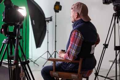 Photo of Movie director sitting on chair in modern film studio