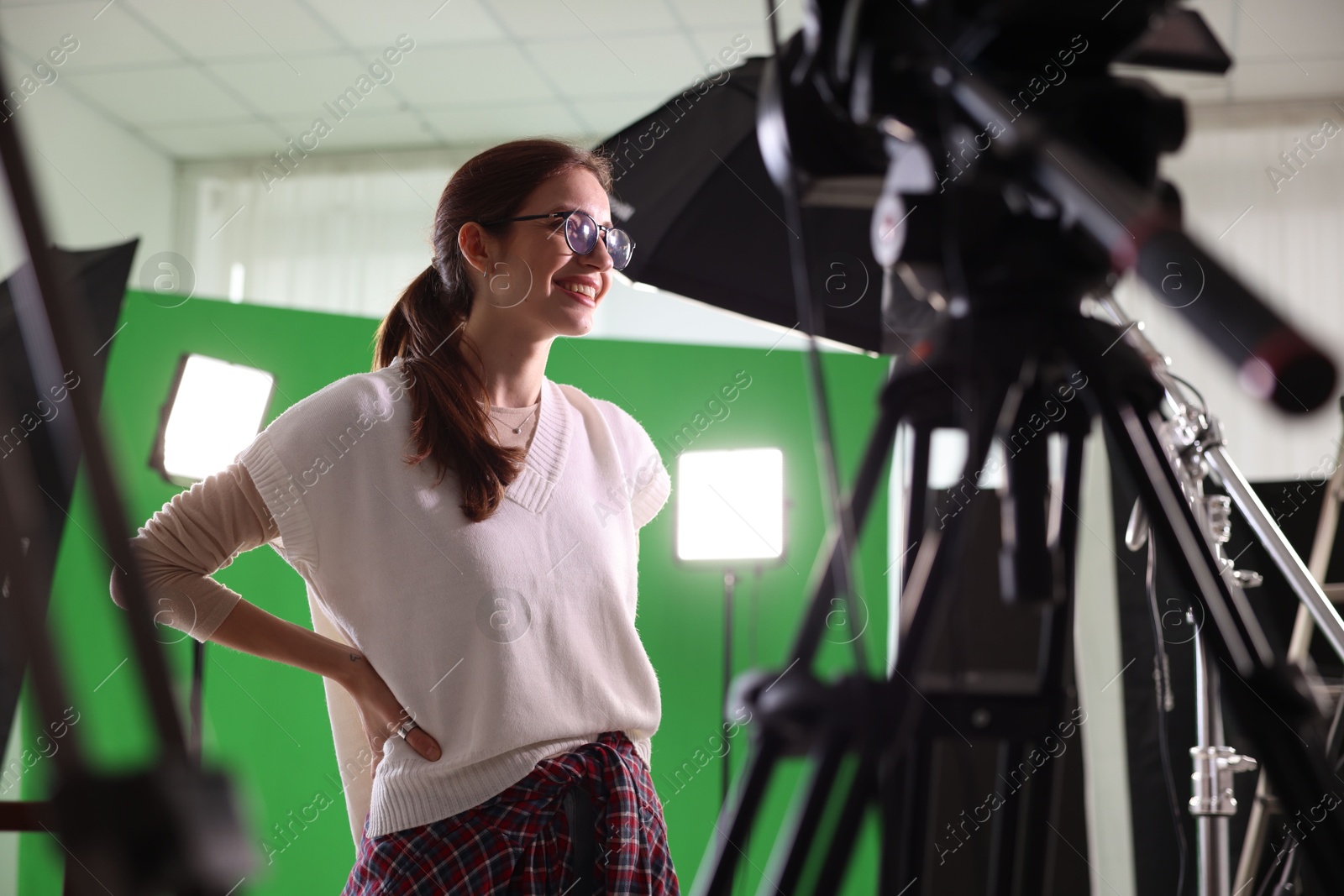 Photo of Happy woman near professional equipment in modern film studio