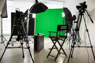 Photo of Camera, chair and other professional equipment in modern film studio