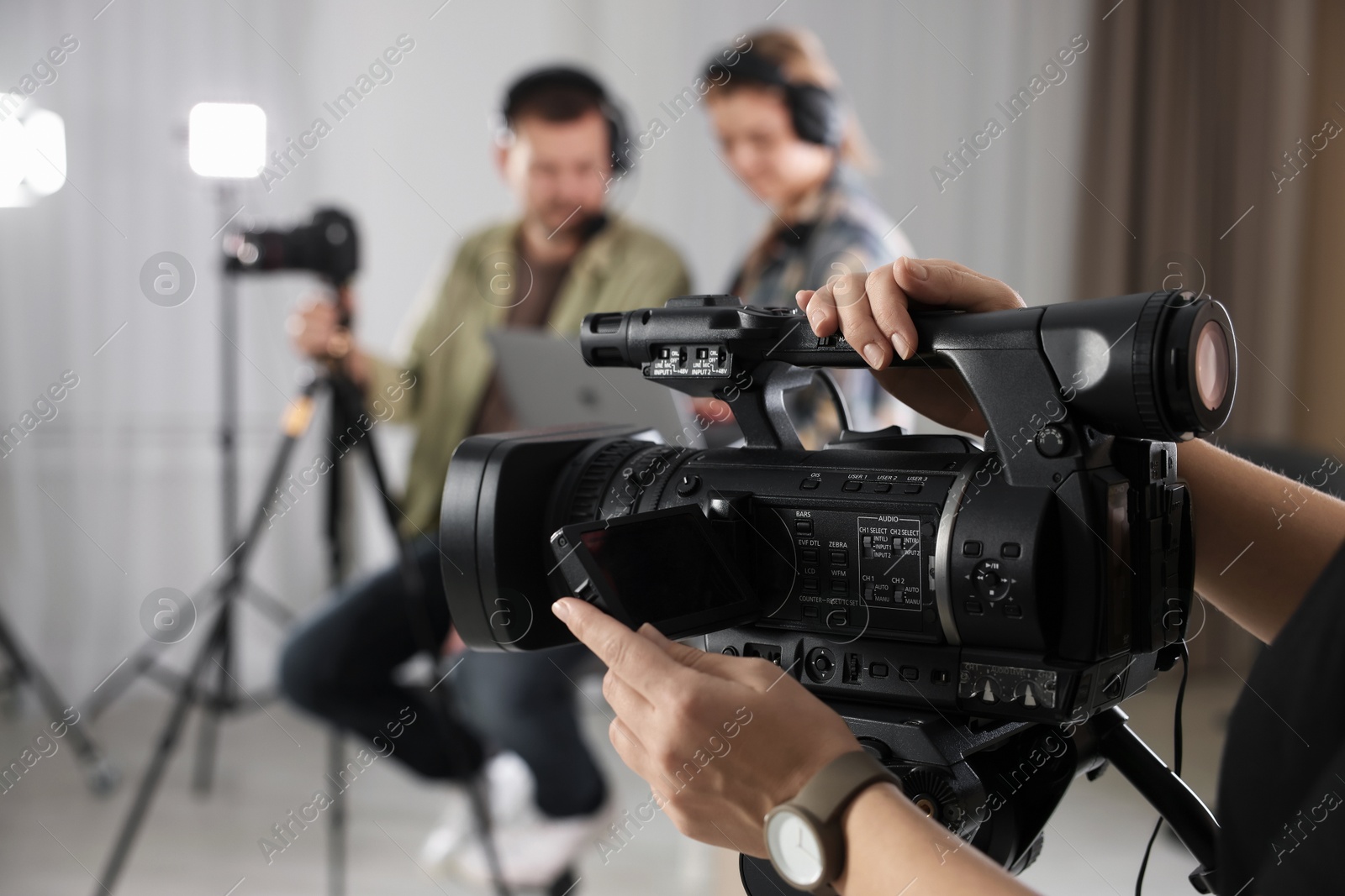 Photo of People working and camerawoman recording them in film studio, selective focus