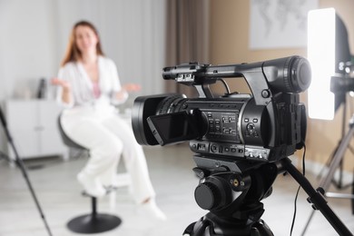 Woman sitting on chair and working in film studio, focus on camera