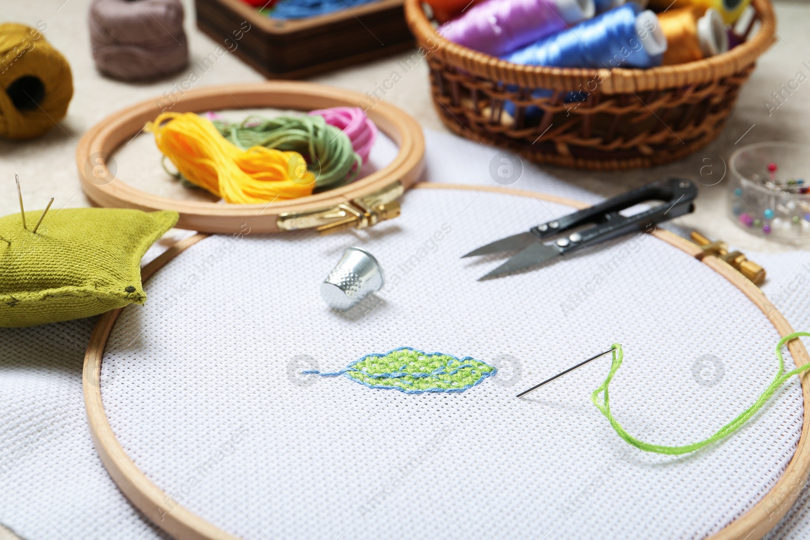 Photo of Embroidery and different sewing accessories on table, closeup