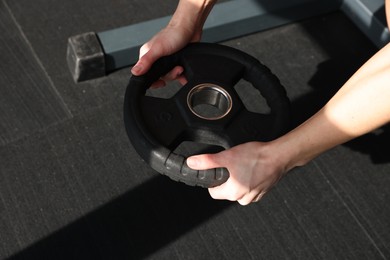 Photo of Woman training with weight plate in gym, closeup