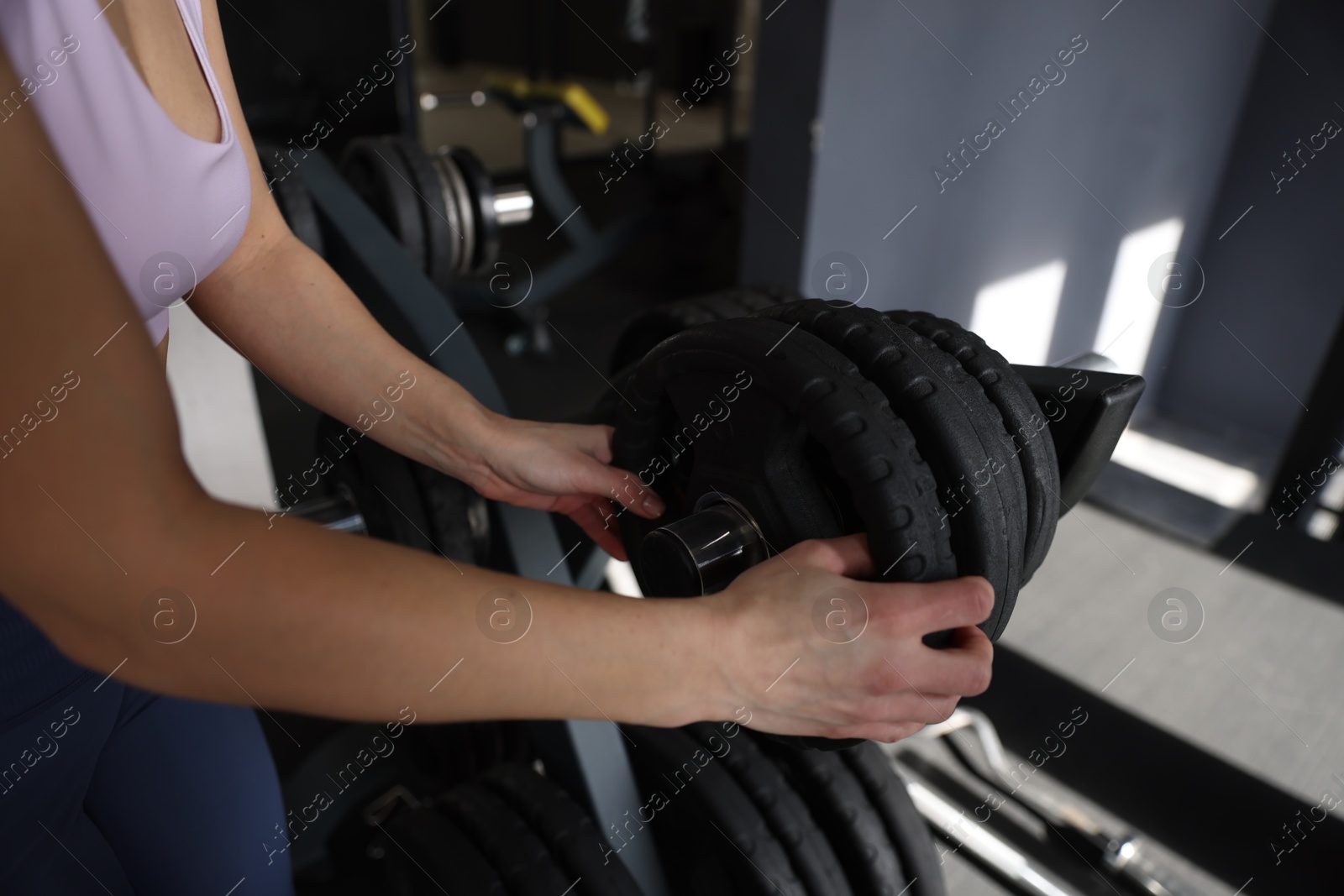 Photo of Woman taking weight plate in gym, closeup