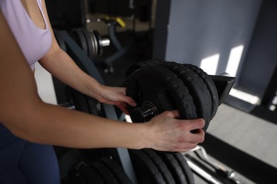 Woman taking weight plate in gym, closeup