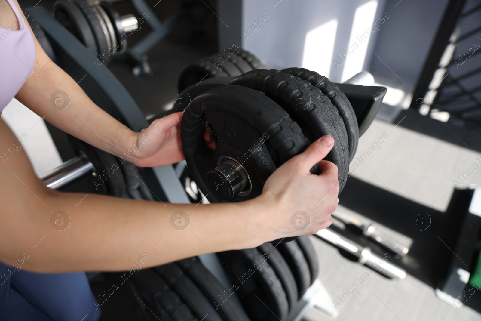 Photo of Woman taking weight plate in gym, closeup