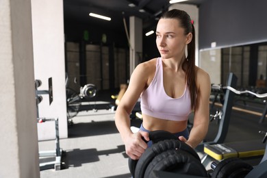 Photo of Athletic woman taking weight plate in gym. Space for text