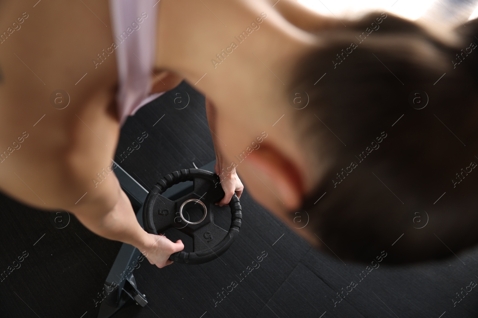 Photo of Woman taking weight plate in gym, above view