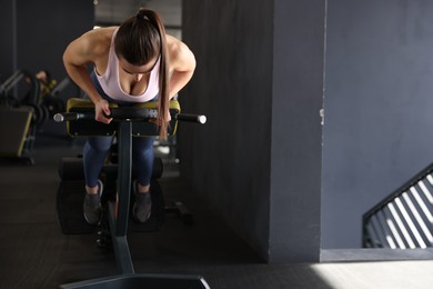 Photo of Athletic woman training with weight plate on t-bar row machine in gym. Space for text