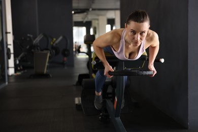 Photo of Athletic woman training with weight plate on t-bar row machine in gym. Space for text