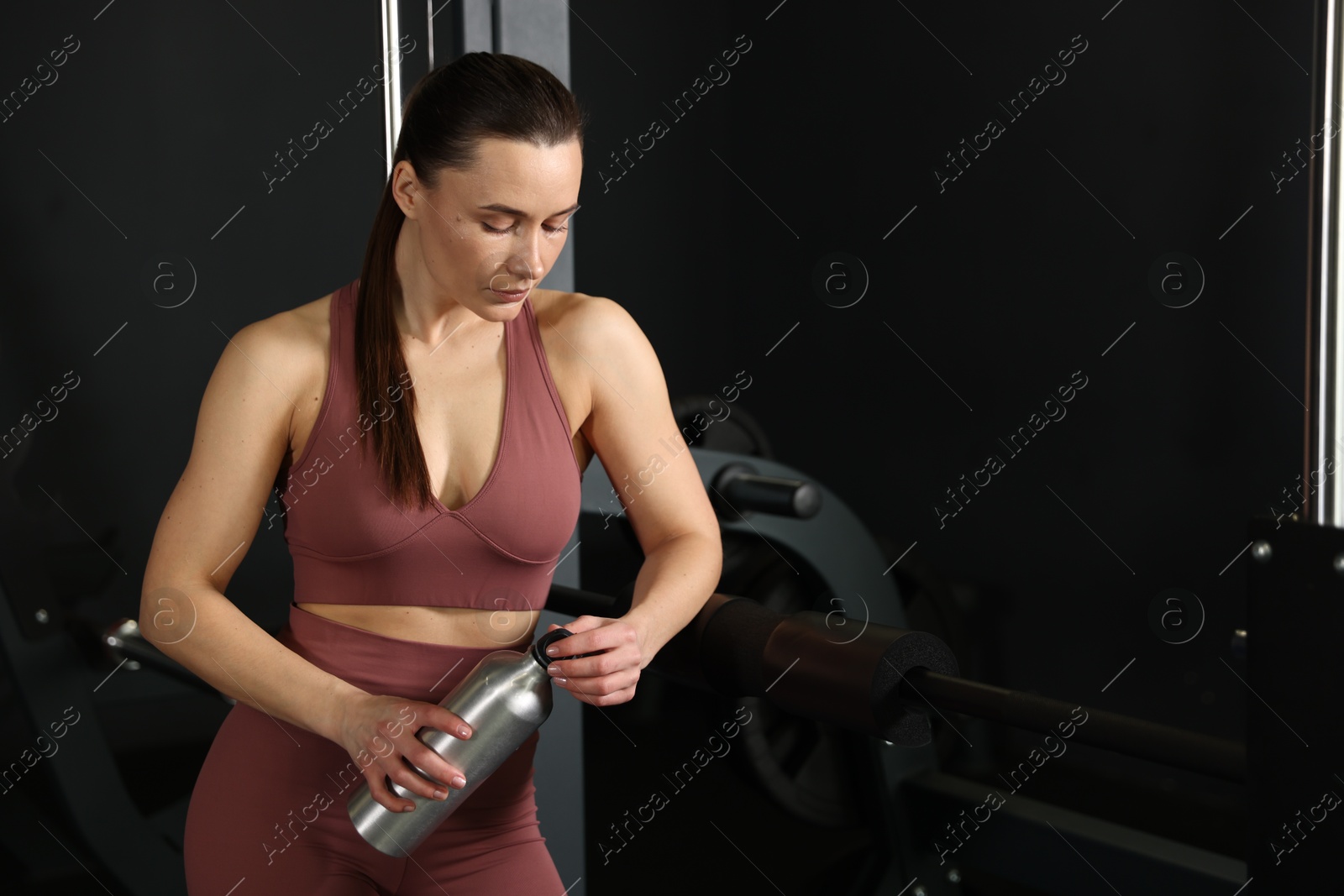 Photo of Athletic woman with thermo bottle in gym. Space for text