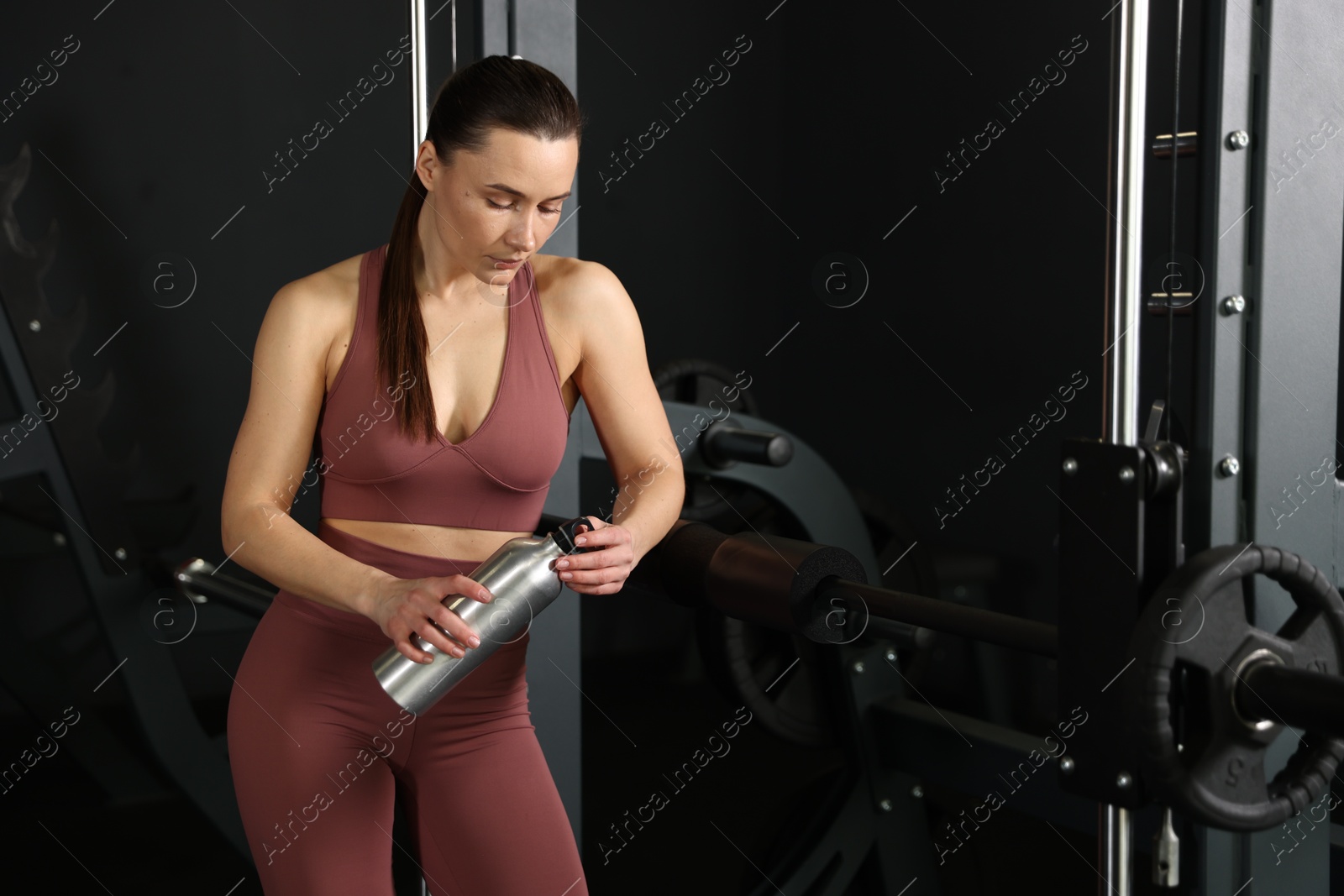 Photo of Athletic woman with thermo bottle in gym. Space for text