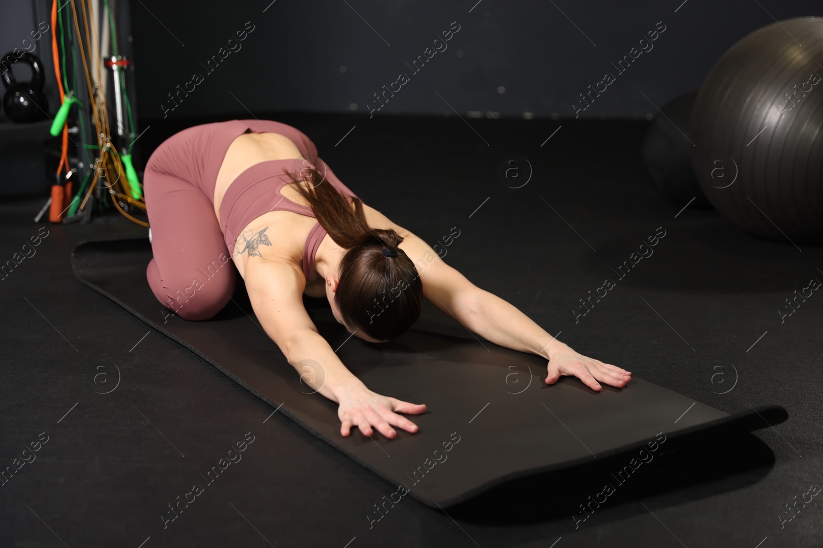 Photo of Athletic woman training on yoga mat in gym