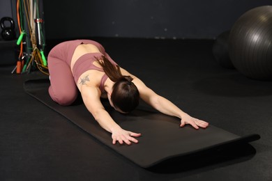 Photo of Athletic woman training on yoga mat in gym