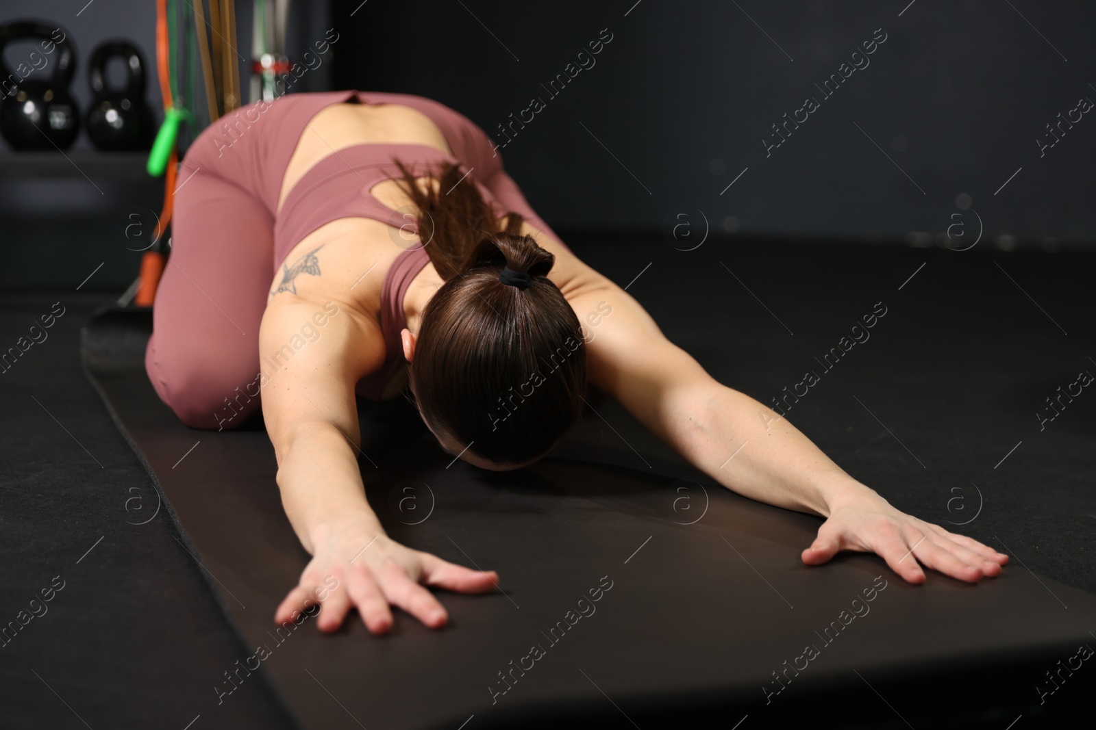 Photo of Athletic woman training on yoga mat in gym