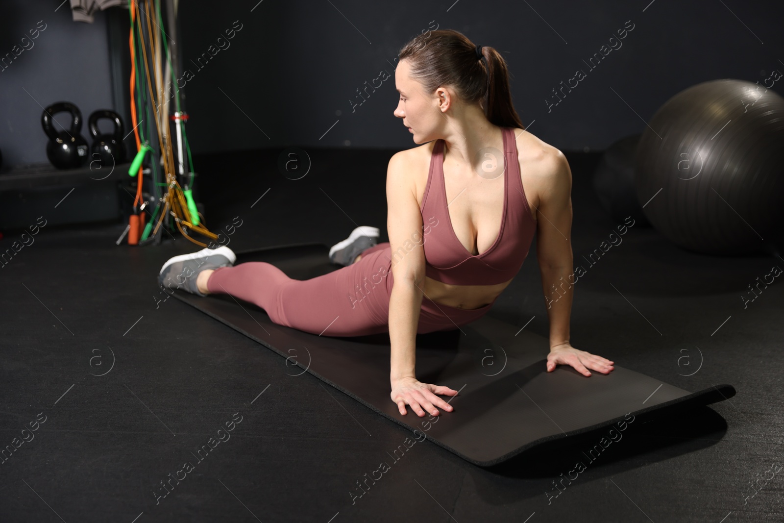 Photo of Athletic woman training on yoga mat in gym