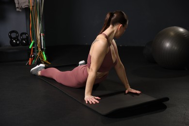 Photo of Athletic woman training on yoga mat in gym