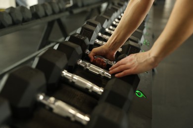 Photo of Woman taking rubber hex dumbbell in gym, closeup