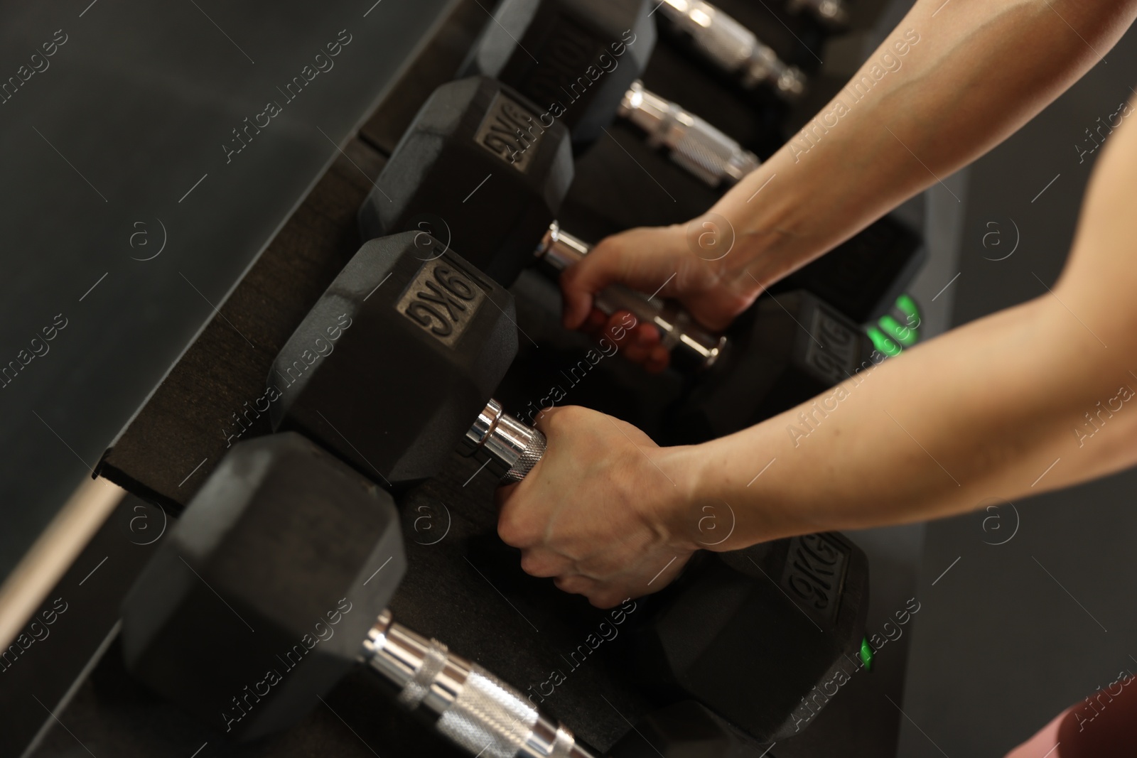 Photo of Woman taking rubber hex dumbbell in gym, closeup