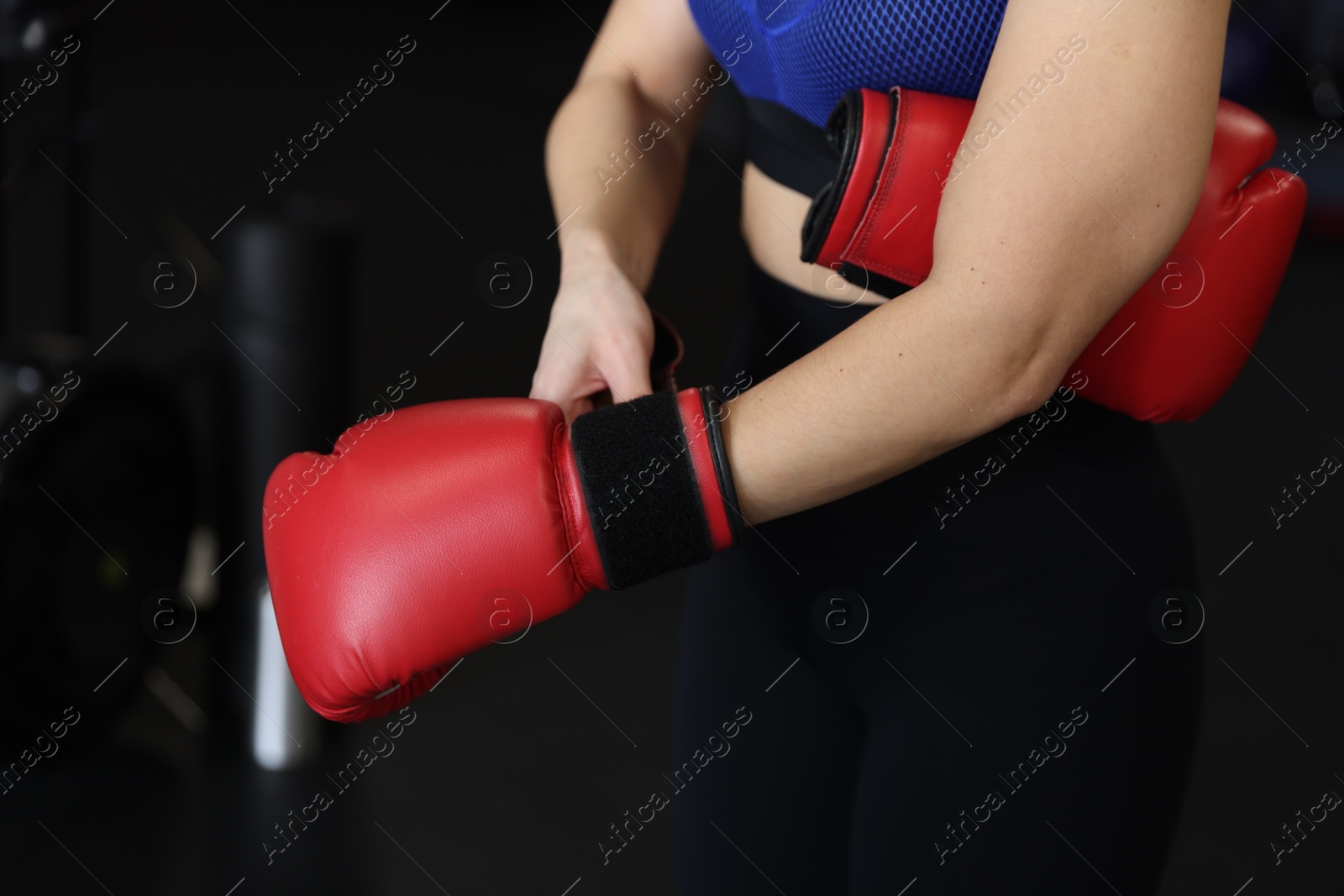 Photo of Woman wearing boxing glove on black background, closeup