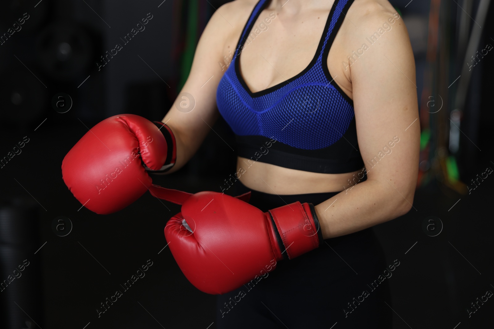 Photo of Woman in boxing gloves on black background, closeup