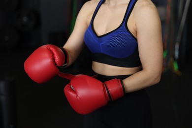 Woman in boxing gloves on black background, closeup