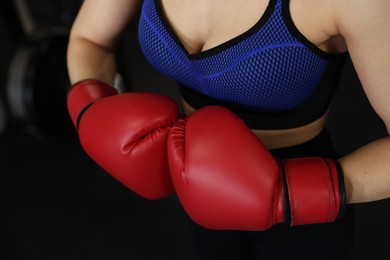 Photo of Woman in boxing gloves on black background, closeup