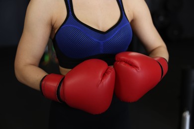 Woman in boxing gloves on black background, closeup