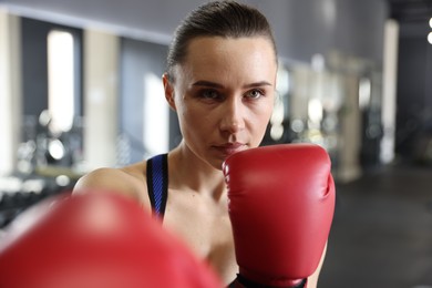 Woman wearing boxing gloves in gym, closeup