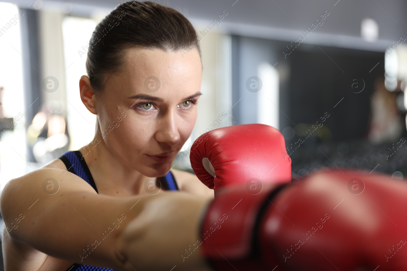 Photo of Woman wearing boxing gloves in gym, closeup